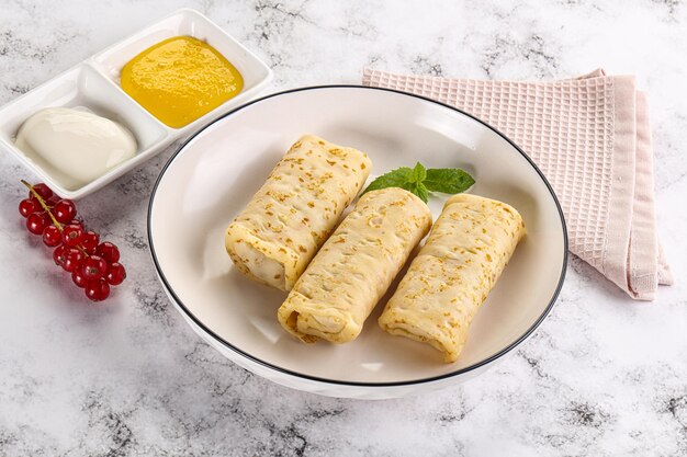 Foto huisgemaakte gevulde pannenkoeken met honing en zure room