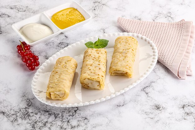 Foto huisgemaakte gevulde zoete pannenkoeken met honing en roomzuur