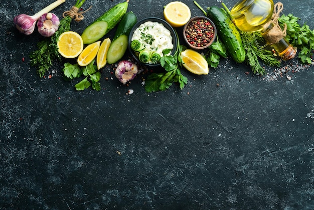 Huisgemaakte Griekse saus met komkommer, citroen en knoflook op een zwarte achtergrond Bovenaanzicht Vrije ruimte voor uw tekst