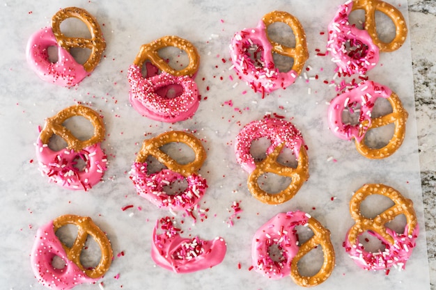 Foto huisgemaakte heerlijke pretzels versierd met roze chocolade en sprinkles.