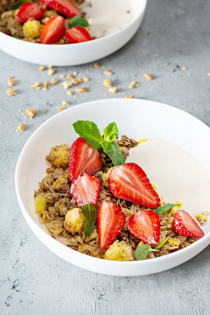 Huisgemaakte knapperige granola met noten, gedroogd fruit, verse aardbeien, munt en yoghurt