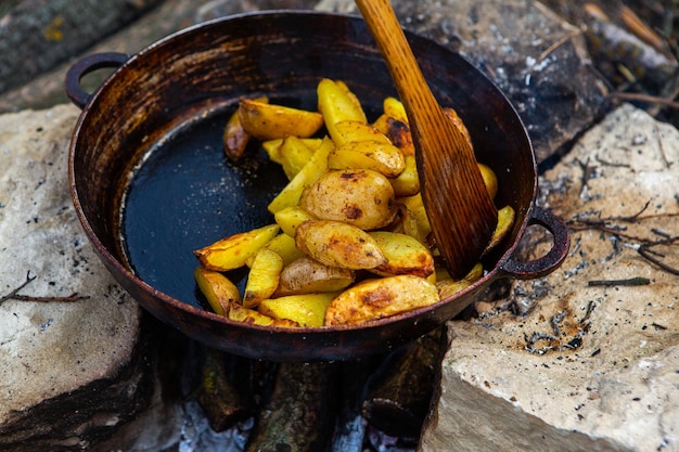 Huisgemaakte krokante aardappelen op een koekenpan op het vuur buiten