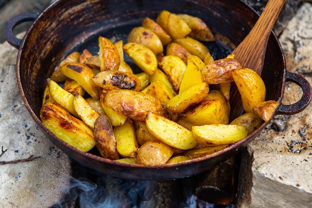 Huisgemaakte krokante aardappelen op een koekenpan op het vuur buiten