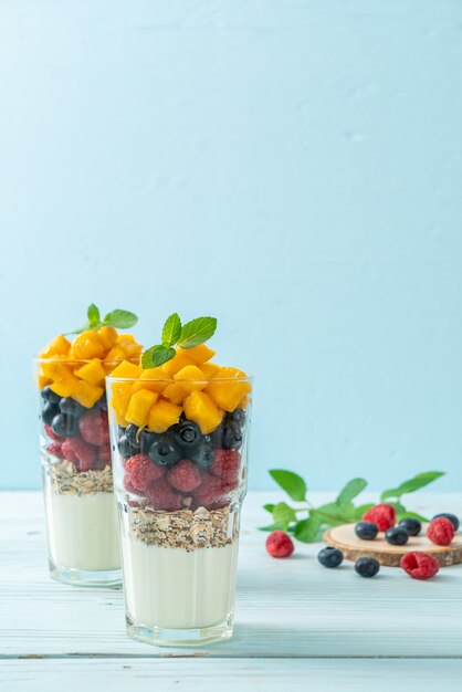 Huisgemaakte mango, framboos en bosbes met yoghurt en granola