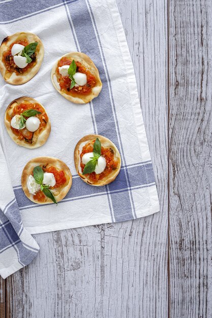Huisgemaakte minipizza's margarita met tomaat, mozzarella en basilicum