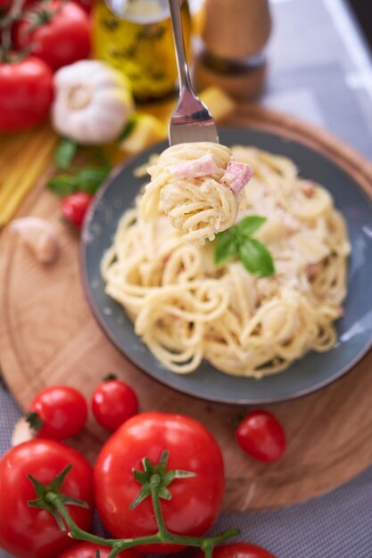 Huisgemaakte pasta carbonara met verse basilicum en parmezaan in keramische schotel