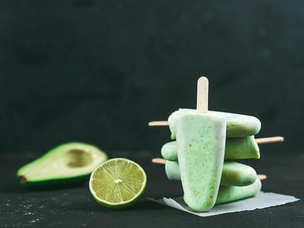 Huisgemaakte rauwe veganistische avocado limoen popsicle Suikervrije niet-zuivelgroene ijs op zwarte achtergrond Kopieerruimte Ideeën en recepten voor gezonde snack dessert of smoothie