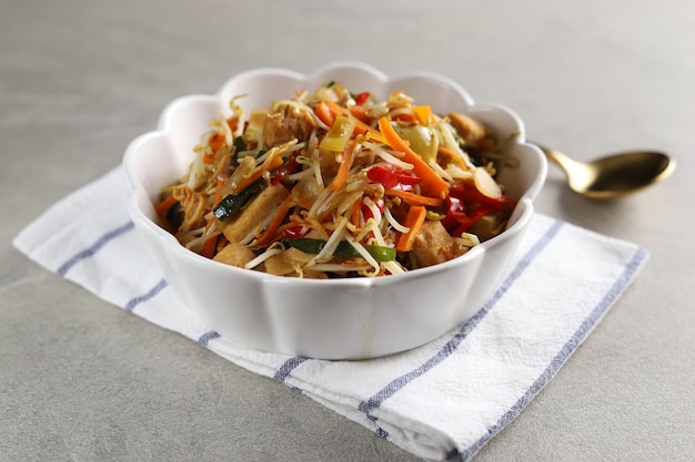 Huisgemaakte roerbaktofu met spruitjes of tumis sayur tauge of toge geserveerd in witte kom