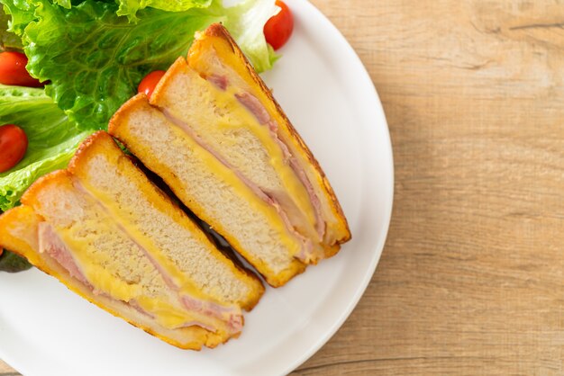 Huisgemaakte sandwich ham kaas met salade op wit bord