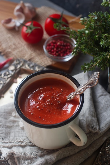 Huisgemaakte tomatensoep in een mok met verse kruiden knoflook rode peper en himalayazout