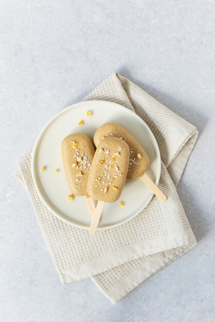 Huisgemaakte vegan ijslolly met chocolade cashewnoten op een bord