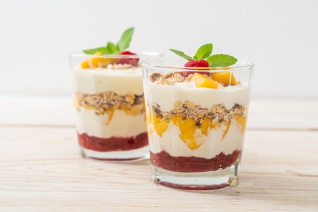 Huisgemaakte verse mango en verse framboos met yoghurt en granola