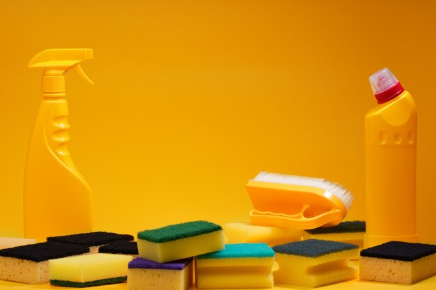 Huishoudelijke schoonmaakmiddelen en sponzen op gele achtergrond