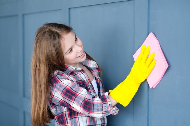 Foto huishoudelijke taken en kinderhulp. klein meisje dat huismuren schoonmaakt.