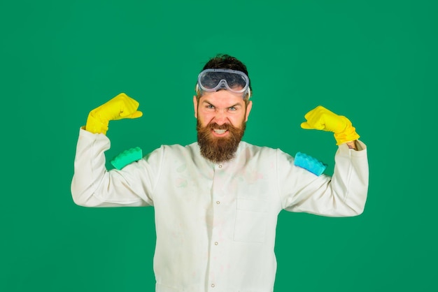 Huishoudster in beschermende handschoenen en bril met sponzen voor het reinigen van bebaarde man houdt