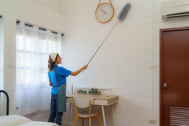 Foto huishoudsters stofzuigen de muren van de slaapkamer met precisie