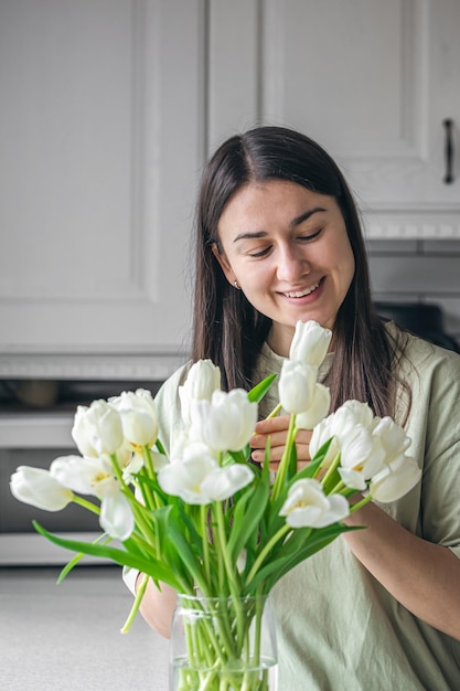 Huishoudvrouw geniet van een boeket bloemen in het interieur van de keuken