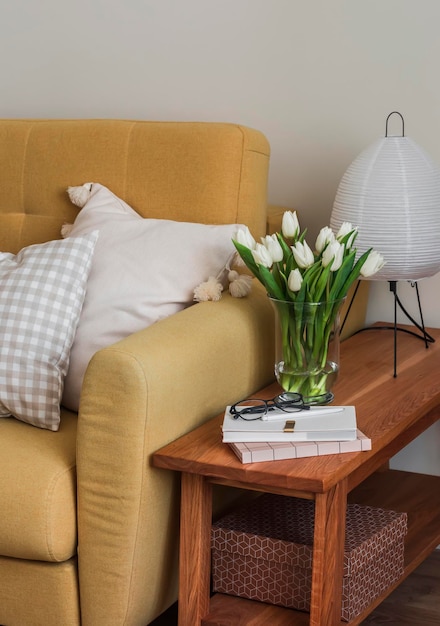 Huisinterieur Een gele bank een houten bank met een papieren lamp een boeket tulpen in een vaas een tijdschrift in het interieur van de woonkamer