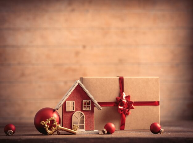 Huisje en sleutel met kerstdoos op houten tafel