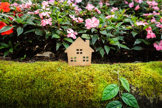 Foto huismodel op groen gras met kleurrijke bloemachtergrond