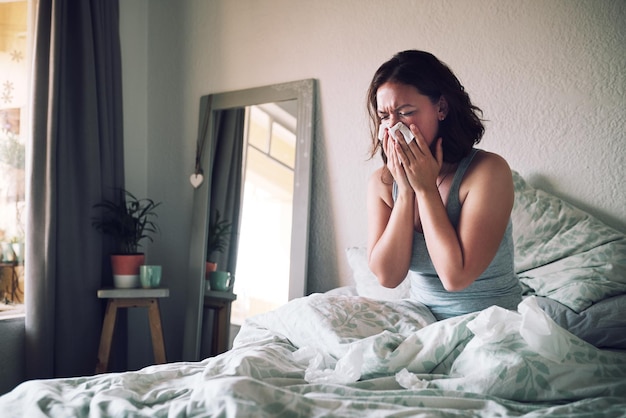 Huispapier en vrouw met griepallergie en ziek op de bank van haar appartement en lijden Vrouwelijke persoon die neus snuit of meisje in haar slaapkamer Gezondheidsprobleem en ziekte met pijn moe of uitgeput