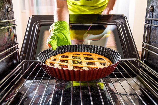 Huisvrouw bereidt taarten in de oven thuis, uitzicht vanaf de binnenkant van de oven. Koken in de oven.