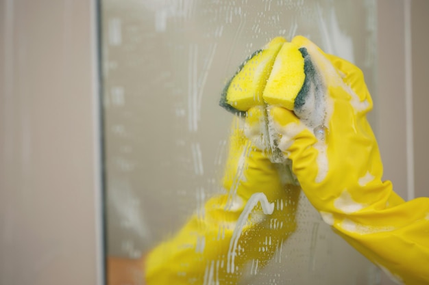 Huisvrouw die de spiegel in de badkamer schoonmaakt