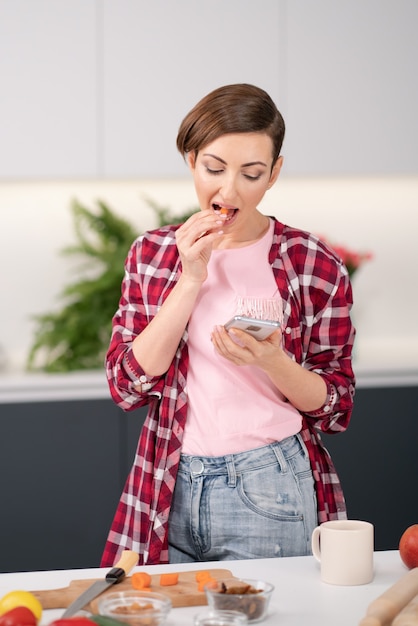 Huisvrouw die e-mail controleert of sms't of foto's van eten plaatst voor haar sociale media die haar gebruiken