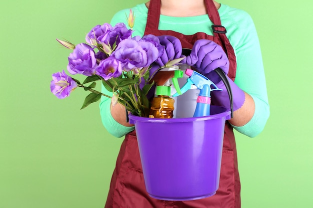 Huisvrouw emmer met reinigingsapparatuur houden op kleur achtergrond Conceptuele foto van voorjaarsschoonmaak