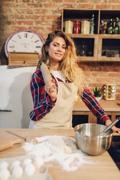 Huisvrouw in een schort met deegroller in de hand