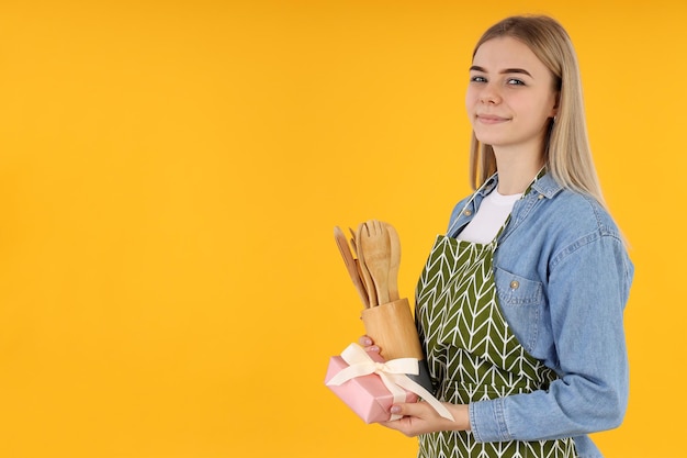 Huisvrouw met geschenkdoos op gele achtergrond