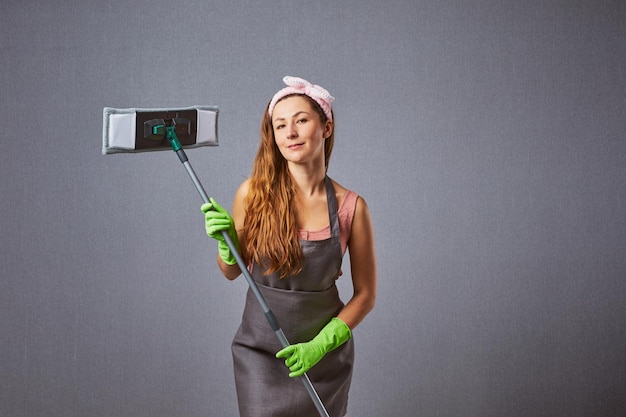 Foto huisvrouw schoonmaken rond met een dweil op grijze achtergrond vrouwelijke wasmachine bedrijf dweil