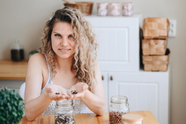 Huisvrouw sorteert bonen in keuken Krullende vrouw houdt bonen in haar handen Vegetarisch eten