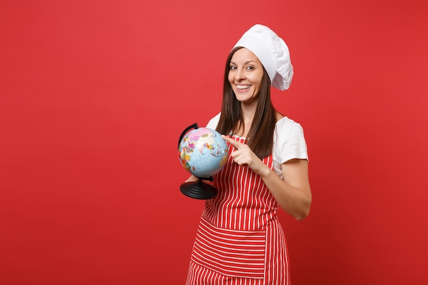 Huisvrouw vrouwelijke chef-kok of bakker in gestreepte schort, wit t-shirt, toque chef-koks hoed geïsoleerd op rode muur achtergrond. huishoudster vrouw met in handpalmen earth wereldbol. bespotten kopie ruimte concept.