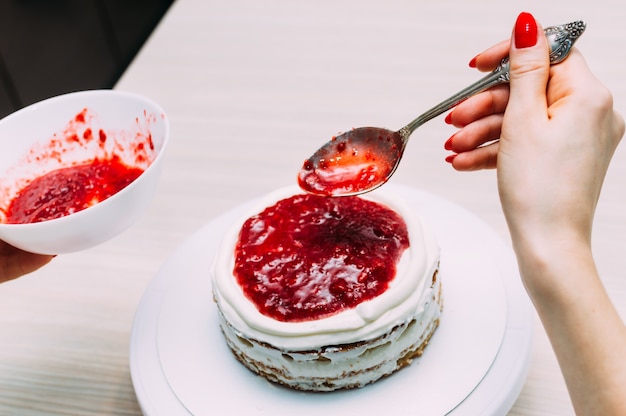 Huisvrouw zet jam tijdens het maken van biscuitgebak. vrouw handen