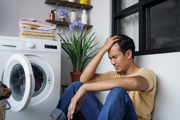 Huiswerk. benadrukt Aziatische Man doet was thuis laden van kleren in de wasmachine