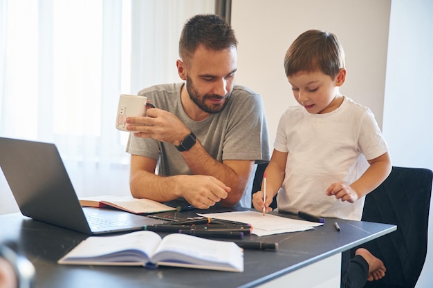 Huiswerk doen Vader en zoon zijn thuis aan de tafel