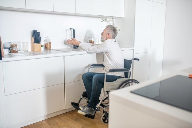 Huiswerk. Rijpe gehandicapte man die thuis wat huishoudelijk werk doet