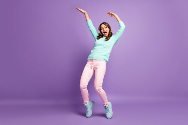 Huiveringwekkende grappige dame handen opsteken dansen jeugd moderne bewegingen gekke student dragen casual pluizige pullover pastel roze broek schoenen.