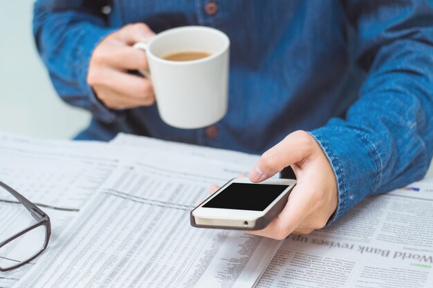 人間の飲み物のコーヒー彼は携帯電話（ヴィンテージトーン）を使用しています