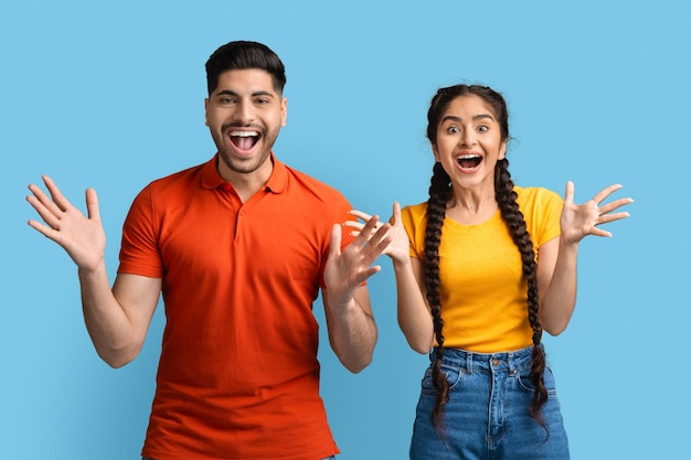 Human emotions portrait of surprised young arab couple spreading hands with excitement