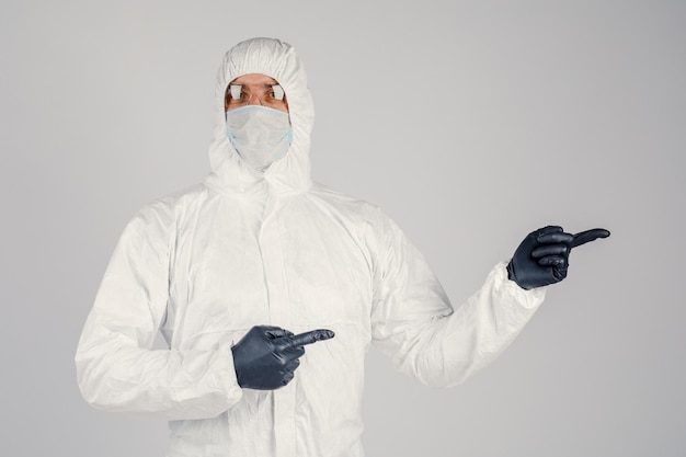 A human epidemiologist in a disposable antiepidemic antibacterial isolation suit shows hand gestures on a white background Epidemic and medical concept