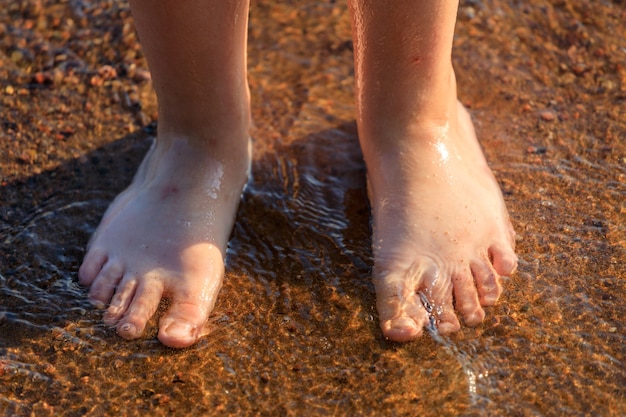 Photo human feet stand on the sand on the beach. high quality photo