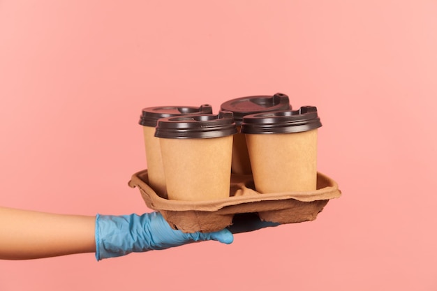 Human hand in blue surgical gloves holding and showing cups of hot takeaway mug drink in hand