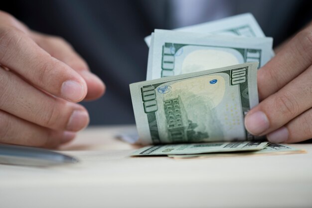 Human hand counting hundred US dollar banknote.