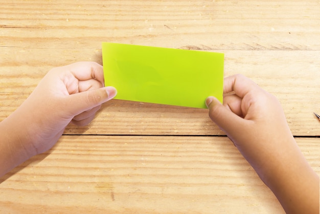 Human hand folding a colored paper wooden background