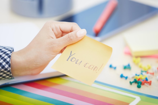 Human hand holding adhesive note with you can text