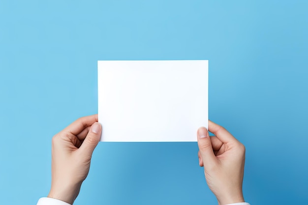 A human hand holding a blank sheet of white paper or card isolated on blue background