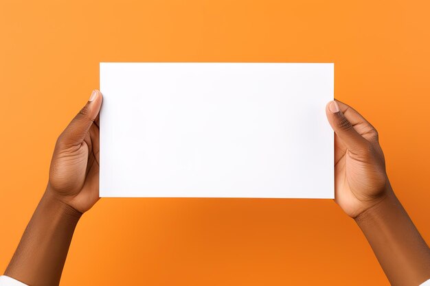 A human hand holding a blank sheet of white paper or card isolated on orange background