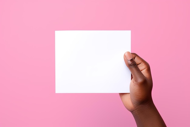 A human hand holding a blank sheet of white paper or card isolated on pink background